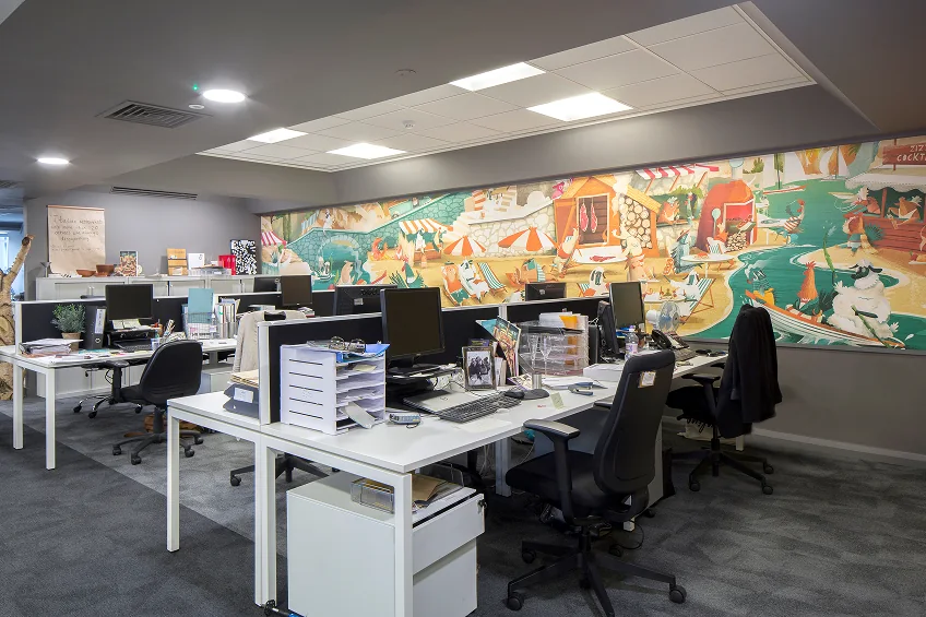 Colourful illustrated wall mural behind desks in an office