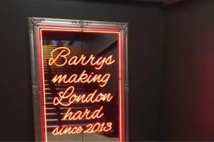 Red illuminated Barrys lettering on an interior wall